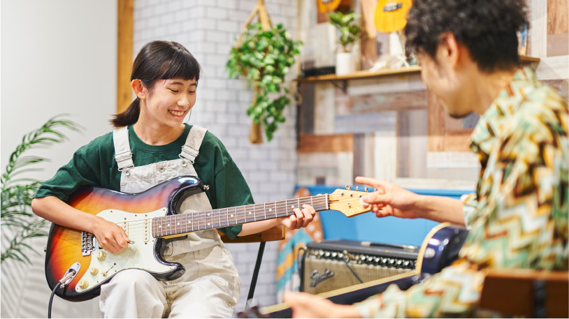 エレキギターを持つ女の子と講師