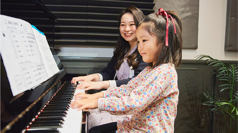 ピアノを弾いている子供と講師